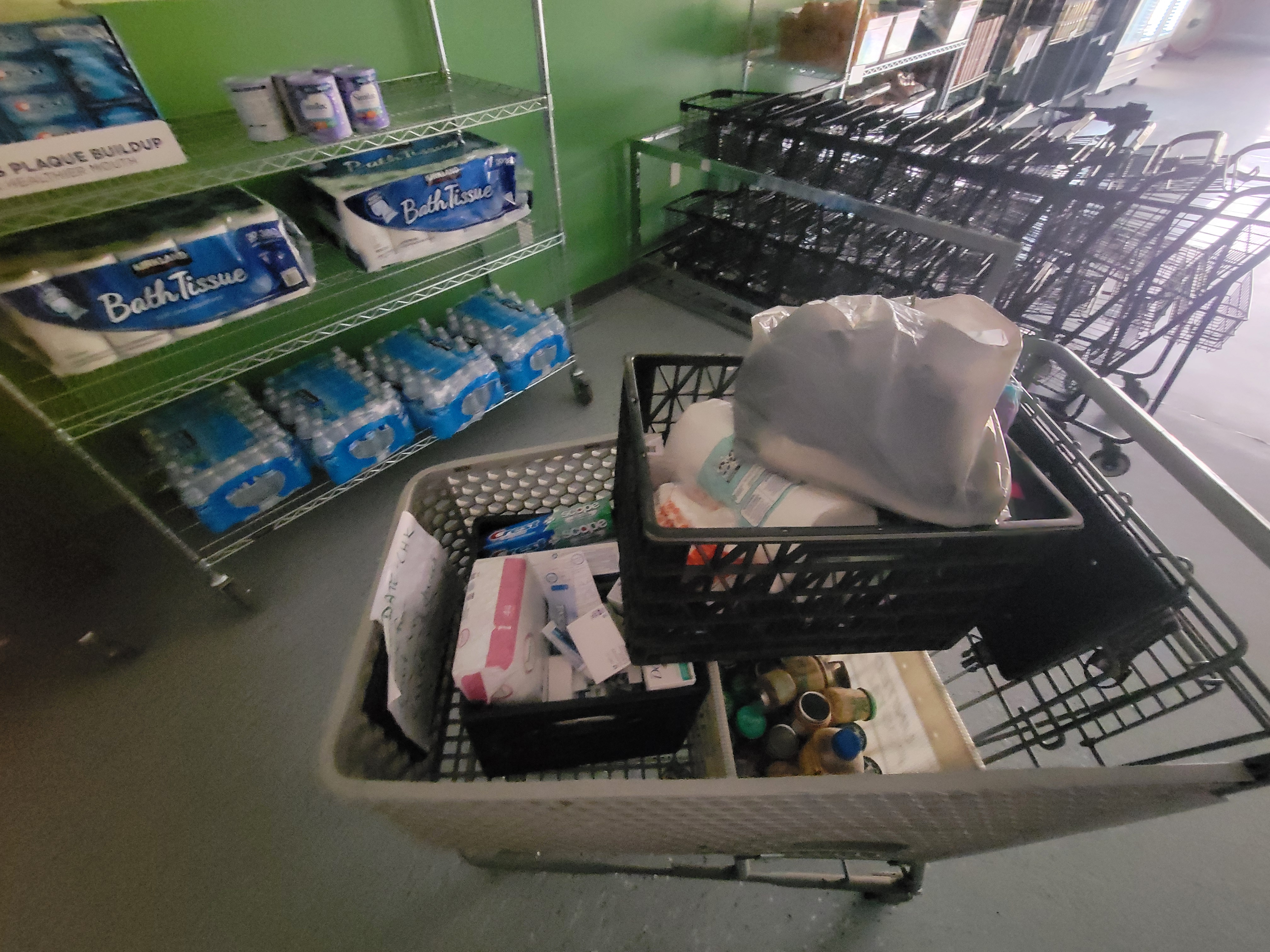 Household items on a shelf and a shopping cart next to rows of shopping carts.